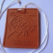 Die Stadtlaufmedaille ist rechteckig aus braunem Ton mit einer weißen Kordel. Auf der Platte sind ein stilisierter Läufer, das Jahr 2020 und die Beschriftung 14. Eberswalder Stadtlauf als Relief abgebildet.