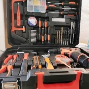 Der Werkzeugkoffer ist rechtwinklig geöffnet. und von vorn fotografiert. In ihm befinden sich ein Akkuschrauber, verschiedene Bohrer, Zangen, Hammer und weiteres Zubehör.