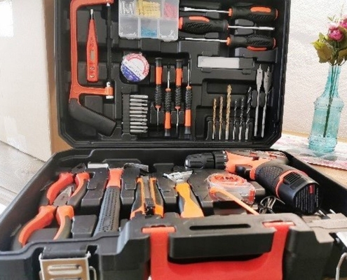 Der Werkzeugkoffer ist rechtwinklig geöffnet. und von vorn fotografiert. In ihm befinden sich ein Akkuschrauber, verschiedene Bohrer, Zangen, Hammer und weiteres Zubehör.