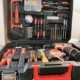 Der Werkzeugkoffer ist rechtwinklig geöffnet. und von vorn fotografiert. In ihm befinden sich ein Akkuschrauber, verschiedene Bohrer, Zangen, Hammer und weiteres Zubehör.