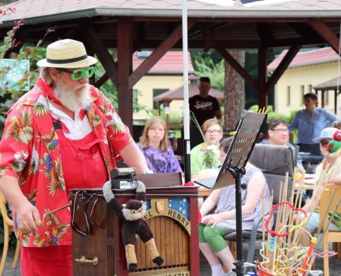 Clown Henry ist bekleidet mit roter Latzhose, roter, bedruckt er Jacke und weißem Strohhut. Er bedient seine Drehorgel (Leierkasten). Vorn an der Drehorgel steht die Aufschrift: Orgel Henry. Auf der Orgel steht eine kleine Kasse, an der ein kleiner Plüsch-Affe hängt. Hinter Orgel-Henry sitzt junges Publikum.