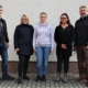 Der neu gewählte Betriebsrat hat sich zum Gruppenfoto vor einer helle Wand der Werkstatt aufgestellt. Von links nach rechts sind das: Thomas Hensel, Christiane Engel, Janine Schurkus, Jeanette Schütze und Thomas Hesse.. Alle lächeln.