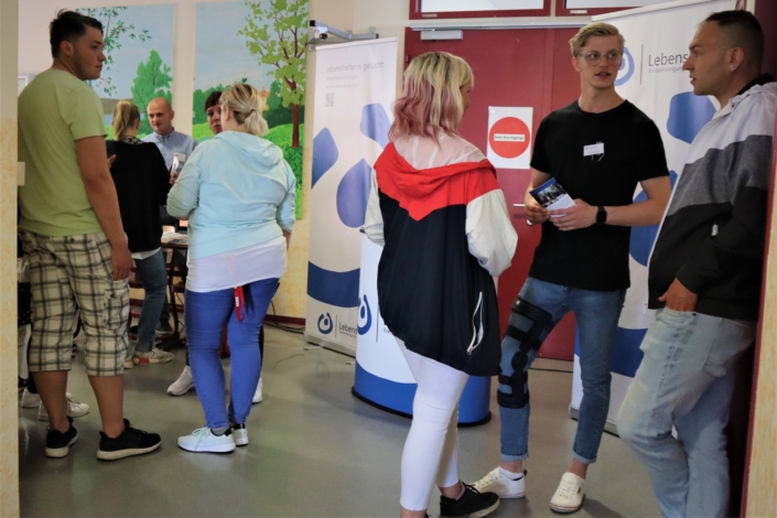 Am Stand haben sich drei kleine Gruppen gebildet. Herr Sallai-Balogh unterhält sich mit einer jungen Frau. Dahinter warten drei weitere junge Ratsuchende.. Rechts im Bild sprich der junge Mitarbeiter mit einer Frau und einem jungen Mann.