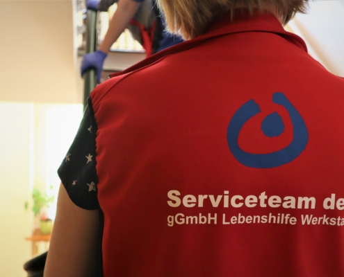 Nahaufnahme des oberen Rückenteils der Weste der Teamöleitern mit dem Logo der Lebenshilfe und der Aufschrift "Serviceteam der gGmbH Lebenshilfe Werkstatt".