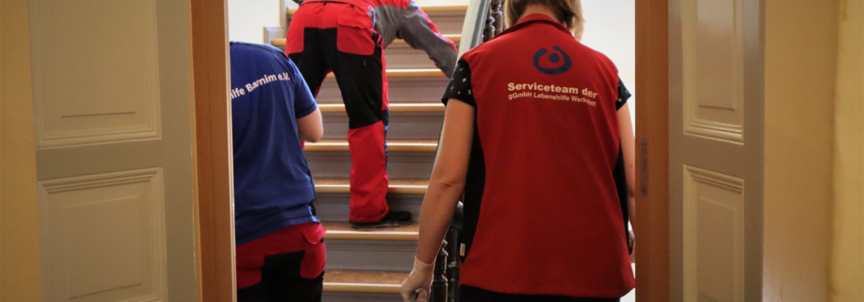 Die Gruppenleiterin und zweit Mitglieder des Serviceteams reinigen eine Treppe. Dabei stehen sie mit dem Rücken zum Betrachter.