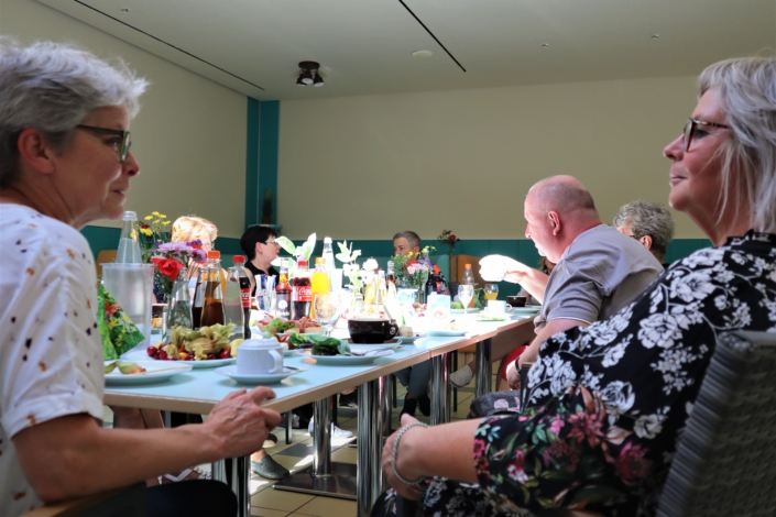 Zeit für den Austausch Frau Winter, Vorsitzende Lebenshilfe, und Frau Bester, Betriebsstättenleiterin Hauptwerkstatt, unterhalten sich angeregt. Aich die anderen Ehrenamtller:innen sind lebhaft im Gespräch.